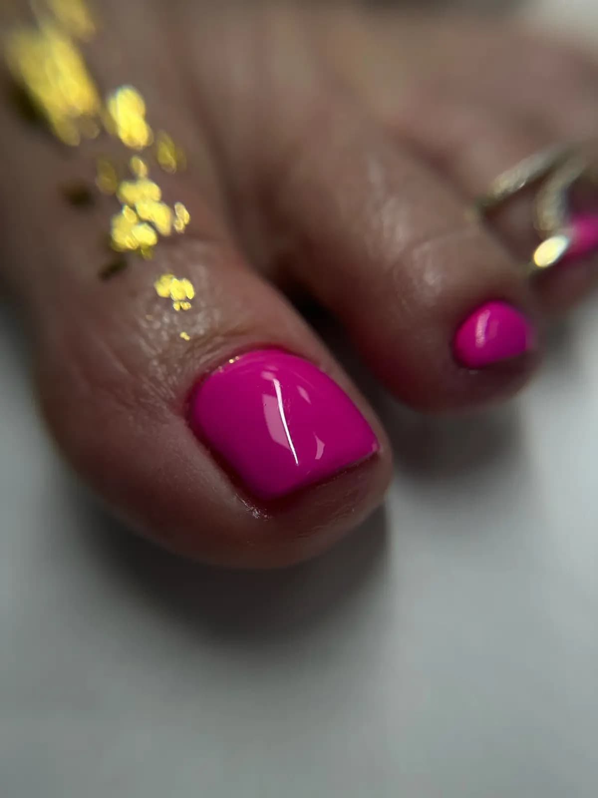 Fuchsia pink gel pedicure with gold foil flakes