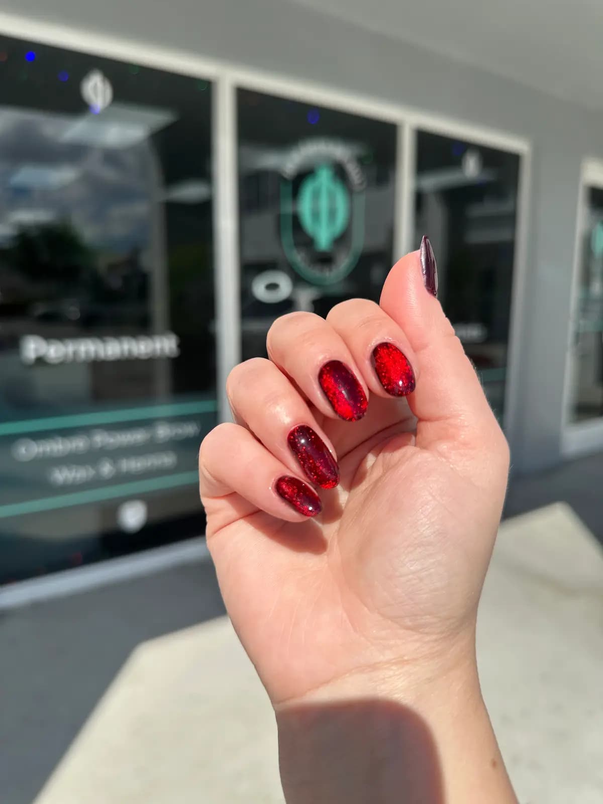Short square nails in dark burgundy gel, shot inside the salon